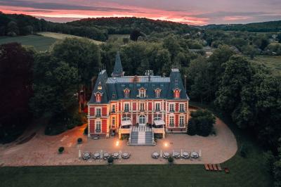 Maison en pierre et colombages entourée de verdure, avec toit en ardoise et fenêtres mansardées.