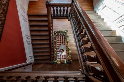 Maison en pierre et colombages entourée de verdure, avec toit en ardoise et fenêtres mansardées.