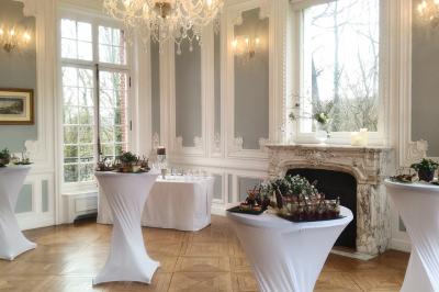 Maison en pierre et colombages entourée de verdure, avec toit en ardoise et fenêtres mansardées.
