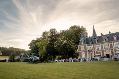Maison en pierre et colombages entourée de verdure, avec toit en ardoise et fenêtres mansardées.