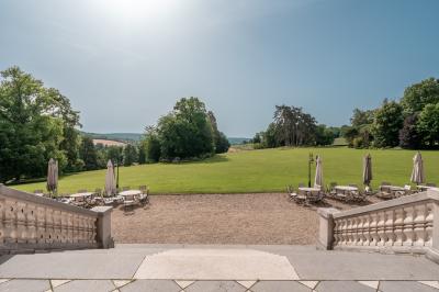 Maison en pierre et colombages entourée de verdure, avec toit en ardoise et fenêtres mansardées.