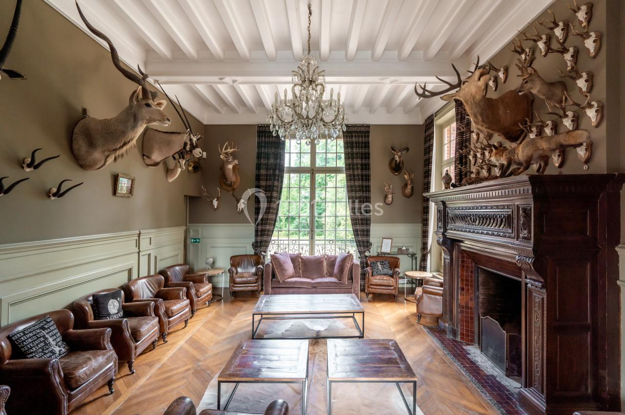 Salle de séjour avec cheminée, mobilier en cuir et murs ornés de trophées de chasse.