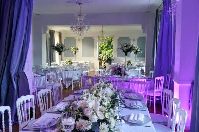 Salle décorée avec des plantes suspendues, des lampes en osier, une table haute et des chaises en métal.