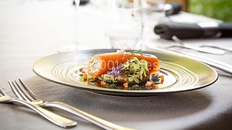 Assiette gastronomique avec roulé de saumon, légumes finement coupés et herbes fraîches, servie sur une table élégante.