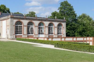 Salle de bain avec cabine de douche arrondie en verre, lavabo encastré et murs carrelés beige.