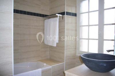 Salle de bain avec cabine de douche arrondie en verre, lavabo encastré et murs carrelés beige.