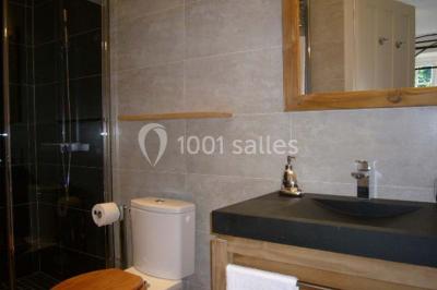 Salle de bain avec cabine de douche arrondie en verre, lavabo encastré et murs carrelés beige.