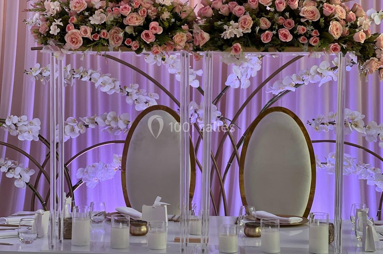Décoration de table élégante avec chaises ovales, fleurs roses et blanches, et bougies sur une nappe blanche.