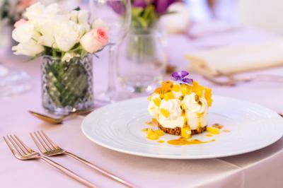 Rouleau croustillant servi sur un lit de légumes colorés avec une garniture florale sur une assiette blanche.