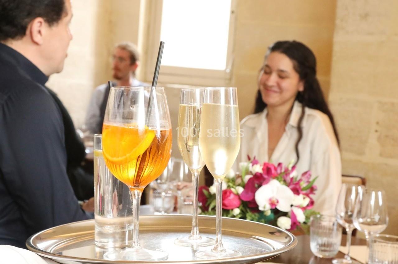 Un plateau avec un cocktail et deux verres de champagne est servi dans un restaurant élégant.