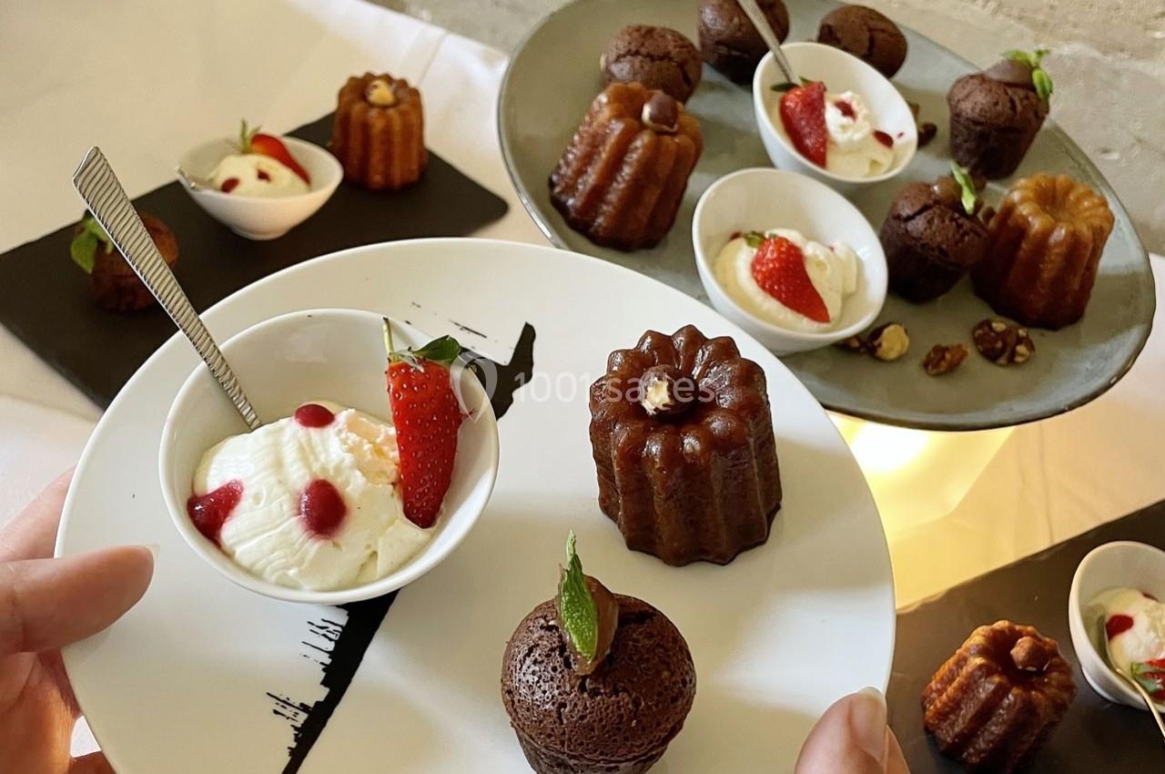 Assortiment de cannelés, moelleux au chocolat et verrines de crème décorées de fraises sur une table de dégustation.