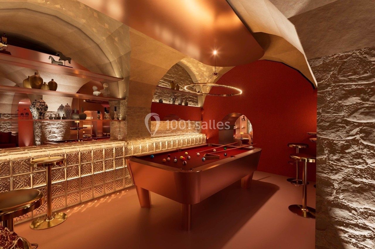 Salle voûtée avec un billard rouge, un bar éclairé et une décoration chaleureuse aux tons rouges et dorés.