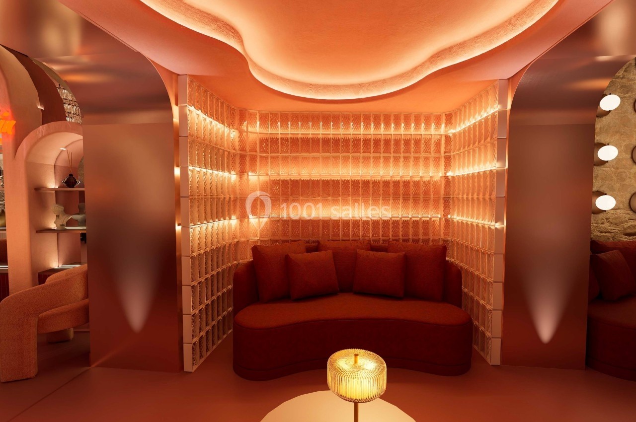 Espace lounge avec banquette incurvée, éclairage tamisé et murs texturés dans des tons chauds.