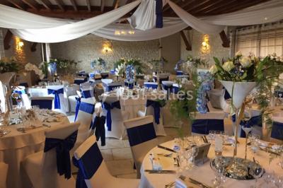 Champ de coquelicots rouges au premier plan avec un bâtiment en pierre et des toits en arrière-plan sous un ciel nuageux.