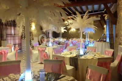 Champ de coquelicots rouges au premier plan avec un bâtiment en pierre et des toits en arrière-plan sous un ciel nuageux.