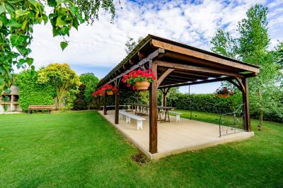 Champ de coquelicots rouges au premier plan avec un bâtiment en pierre et des toits en arrière-plan sous un ciel nuageux.