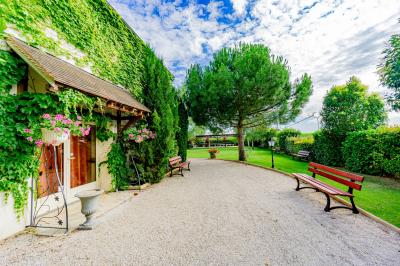 Champ de coquelicots rouges au premier plan avec un bâtiment en pierre et des toits en arrière-plan sous un ciel nuageux.