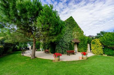 Champ de coquelicots rouges au premier plan avec un bâtiment en pierre et des toits en arrière-plan sous un ciel nuageux.