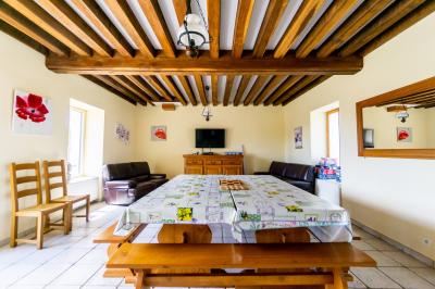 Champ de coquelicots rouges au premier plan avec un bâtiment en pierre et des toits en arrière-plan sous un ciel nuageux.