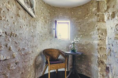 Champ de coquelicots rouges au premier plan avec un bâtiment en pierre et des toits en arrière-plan sous un ciel nuageux.