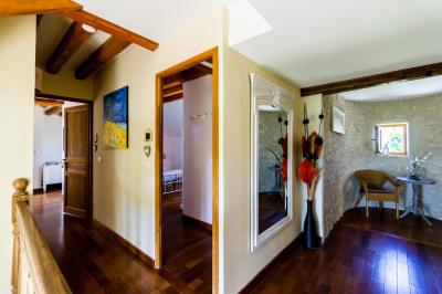 Champ de coquelicots rouges au premier plan avec un bâtiment en pierre et des toits en arrière-plan sous un ciel nuageux.