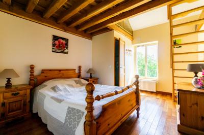 Champ de coquelicots rouges au premier plan avec un bâtiment en pierre et des toits en arrière-plan sous un ciel nuageux.