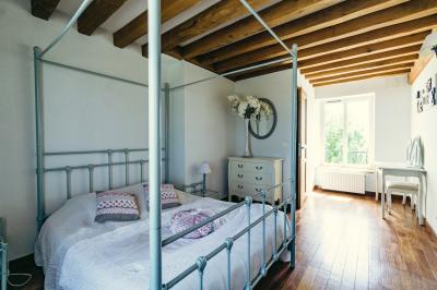 Champ de coquelicots rouges au premier plan avec un bâtiment en pierre et des toits en arrière-plan sous un ciel nuageux.