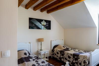 Champ de coquelicots rouges au premier plan avec un bâtiment en pierre et des toits en arrière-plan sous un ciel nuageux.