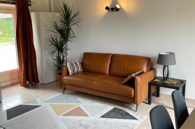 Champ de coquelicots rouges au premier plan avec un bâtiment en pierre et des toits en arrière-plan sous un ciel nuageux.