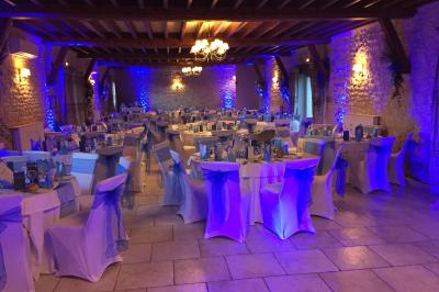 Champ de coquelicots rouges au premier plan avec un bâtiment en pierre et des toits en arrière-plan sous un ciel nuageux.