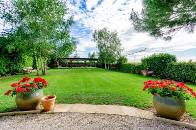Champ de coquelicots rouges au premier plan avec un bâtiment en pierre et des toits en arrière-plan sous un ciel nuageux.