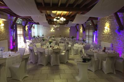 Champ de coquelicots rouges au premier plan avec un bâtiment en pierre et des toits en arrière-plan sous un ciel nuageux.