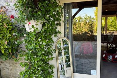 Champ de coquelicots rouges au premier plan avec un bâtiment en pierre et des toits en arrière-plan sous un ciel nuageux.