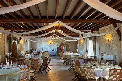 Champ de coquelicots rouges au premier plan avec un bâtiment en pierre et des toits en arrière-plan sous un ciel nuageux.