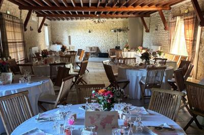 Champ de coquelicots rouges au premier plan avec un bâtiment en pierre et des toits en arrière-plan sous un ciel nuageux.