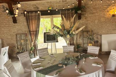 Champ de coquelicots rouges au premier plan avec un bâtiment en pierre et des toits en arrière-plan sous un ciel nuageux.