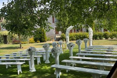 Champ de coquelicots rouges au premier plan avec un bâtiment en pierre et des toits en arrière-plan sous un ciel nuageux.