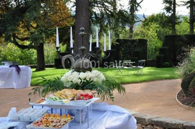 Cour éclairée au crépuscule avec des bâtiments en pierre, des torches allumées et des personnes en arrière-plan.