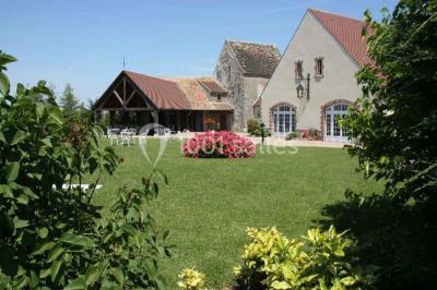 Salle de réception lumineuse avec tables rondes dressées, chaises blanches et décorations florales élégantes.