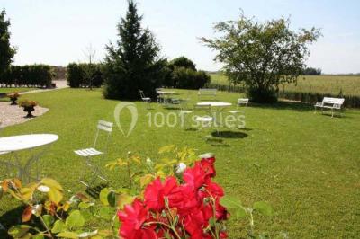 Salle de réception lumineuse avec tables rondes dressées, chaises blanches et décorations florales élégantes.