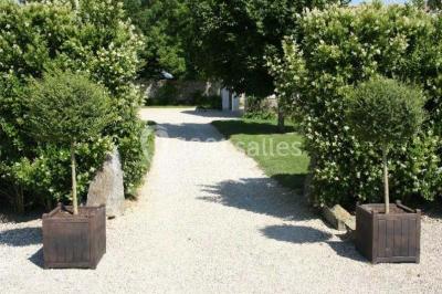 Salle de réception lumineuse avec tables rondes dressées, chaises blanches et décorations florales élégantes.