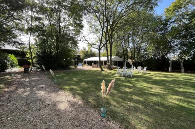 Miniature Jardin des Ecuries Salle de réception décorée pour un événement, avec tables dressées, nappes blanches, fleurs et lumière naturelle.
