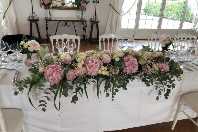 Miniature Table d'honneur du Prieuré Salle de réception décorée pour un événement, avec tables dressées, nappes blanches, fleurs et lumière naturelle.