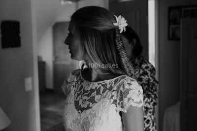 Miniature Toute Belle à Domicile #6 Femme en robe en dentelle blanche, coiffée d'une tresse et d'une fleur, dans un intérieur lumineux.