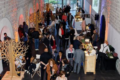Façade vitrée d'un bâtiment moderne avec éclairages rouges, intégrée à des murs en pierre ancienne.
