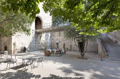 Façade vitrée d'un bâtiment moderne avec éclairages rouges, intégrée à des murs en pierre ancienne.