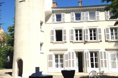 Salle de réunion avec parquet, chaises alignées, table avec projecteur et grandes fenêtres donnant sur l'extérieur.