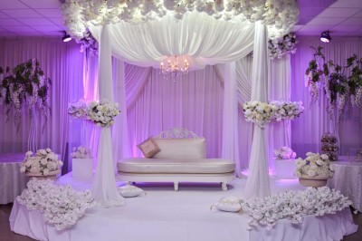 Verres de cocktails colorés garnis de fruits et de feuilles, disposés sur une table lors d'un événement en extérieur.