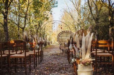 Terrasse en bois ombragée avec des tonneaux en guise de tables, surplombant un plan d'eau entouré de végétation.