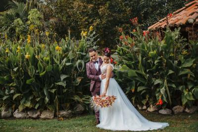 Terrasse en bois ombragée avec des tonneaux en guise de tables, surplombant un plan d'eau entouré de végétation.